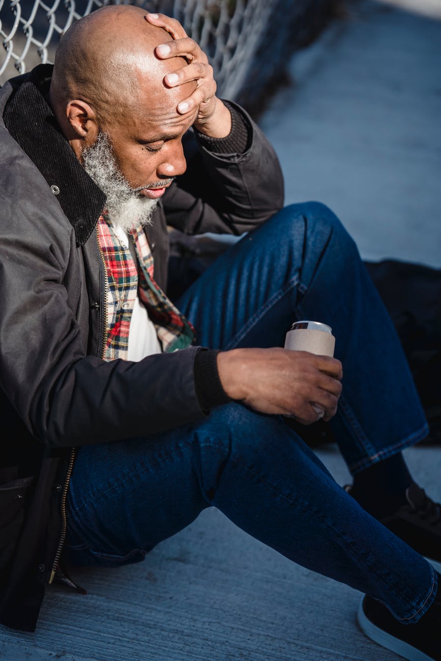 depressed black aged male with beer on street