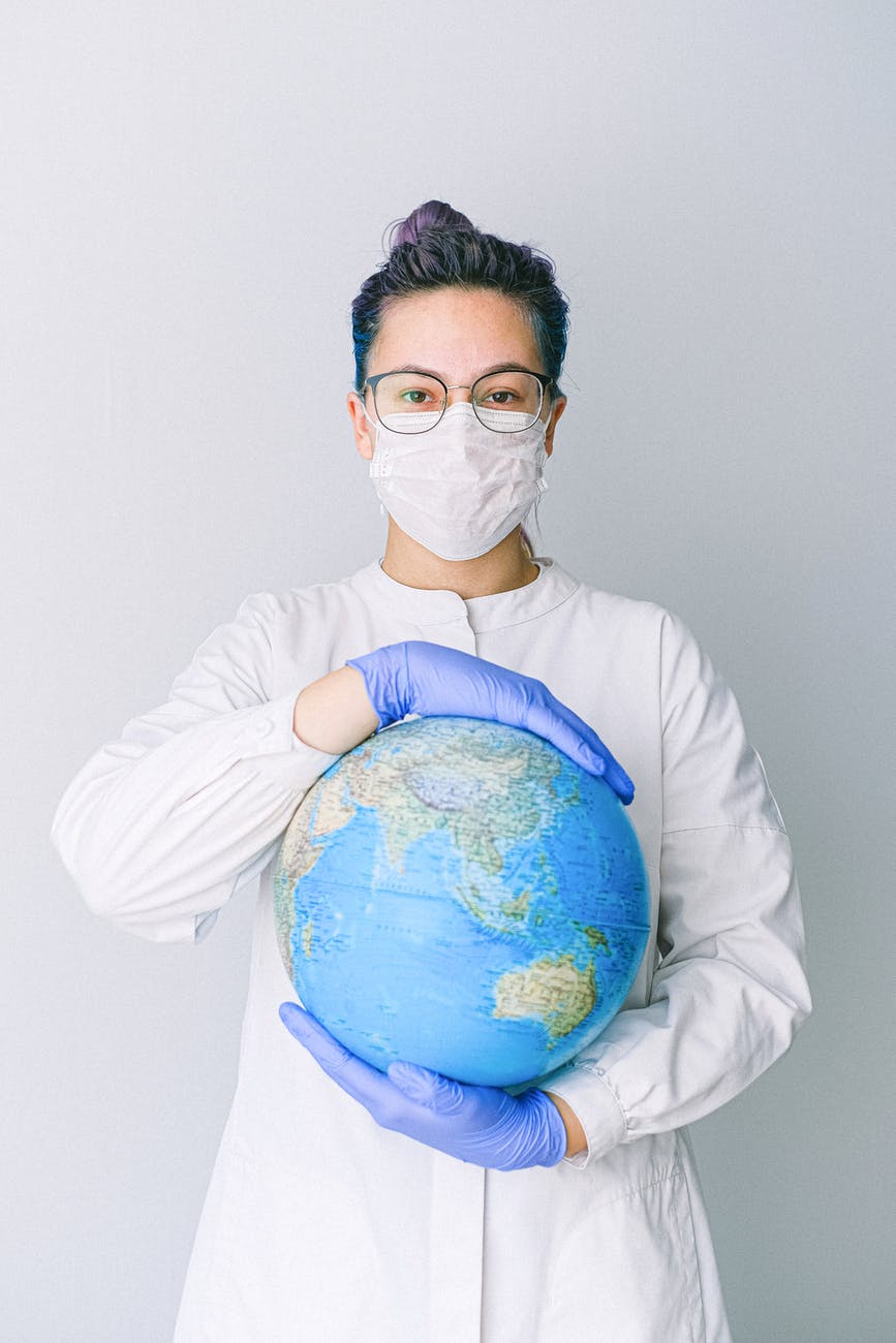epidemiologist person with a face mask and latex gloves holding a globe