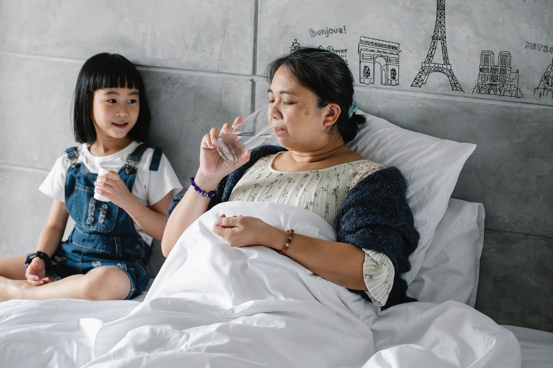 adorable ethnic child giving pills to unhealthy grandmother drinking water in bed - What is House Therapy?