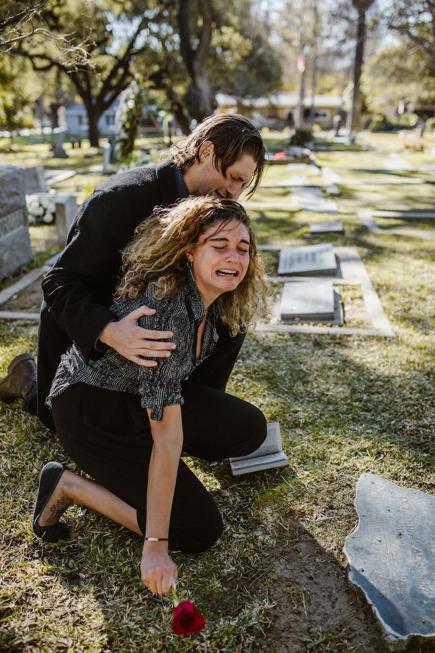 woman crying beside a man in a cemetery the inability of the United States of America to end gun death massacres
