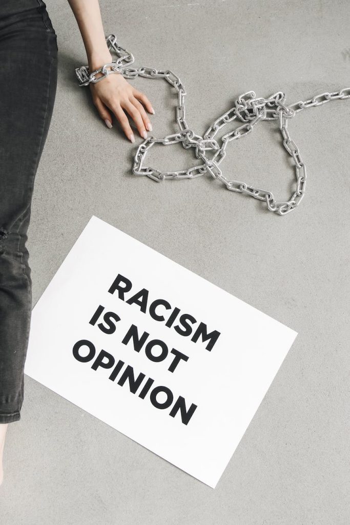 person with chain on hand beside a placard on racism