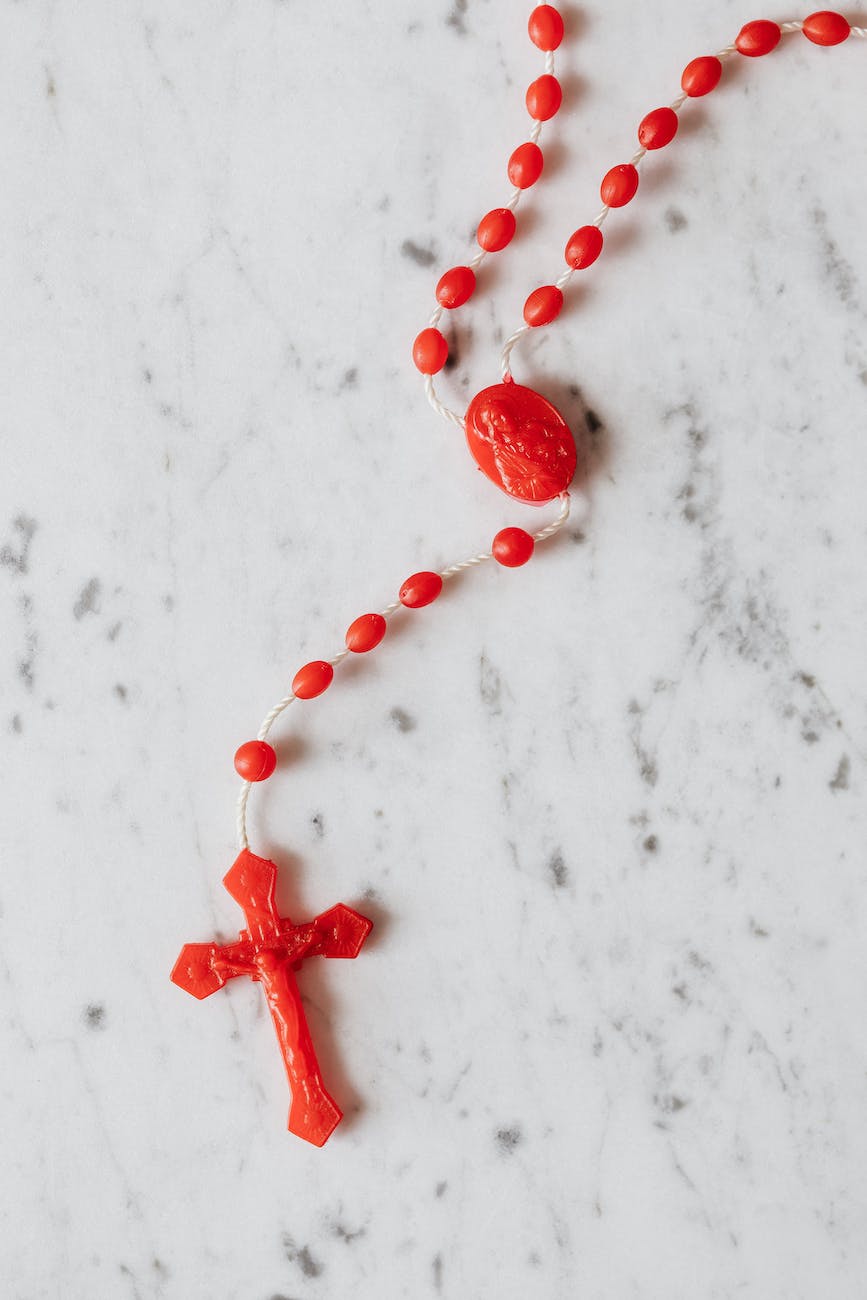 photo of red rosary on white surface