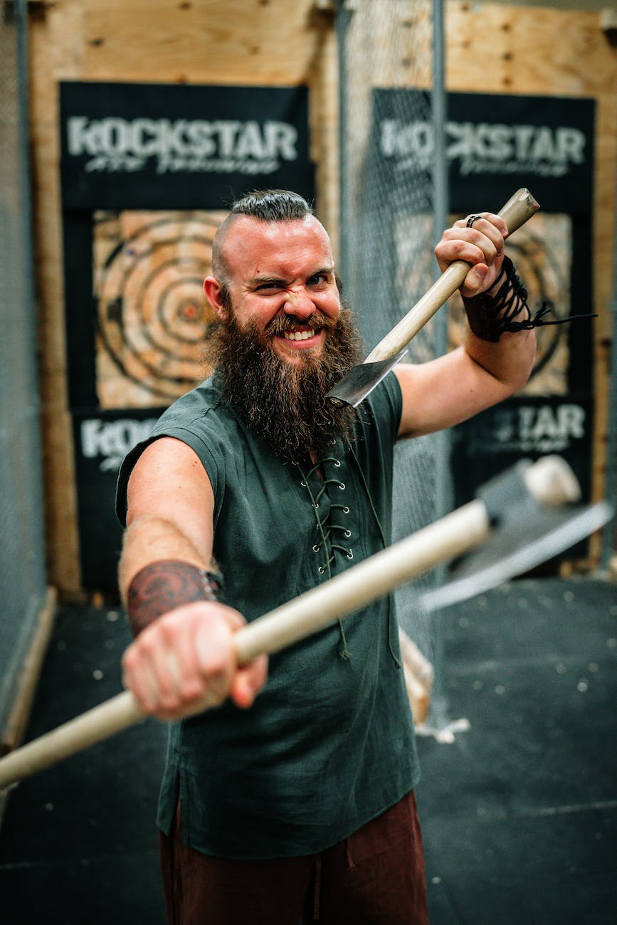 man wearing viking style costume and holding axes