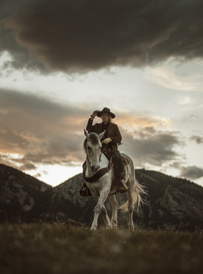 2 men riding horses on grass field during daytime